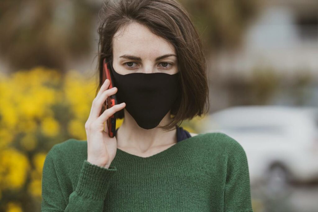 A woman wearing a health mask makes a phone call.